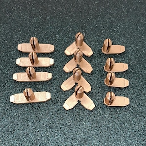 May include: A set of 12 gold-colored metal electrical connectors, some are shaped like a V and others are rectangular.