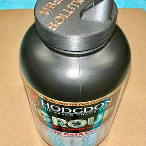 May include: A black plastic container with a black lid. The container is labeled "Hodgdon Group" and "The Brand That's True". The lid has the text "MBS 3D Solutions" printed on it.