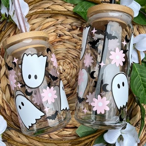 May include: Two clear glass tumblers with bamboo lids and straws. The tumblers feature a spooky Halloween design with pink flowers, bats, and ghosts.