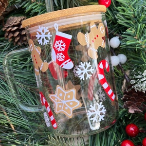 May include: A clear glass mug with a bamboo lid and a straw. The mug has a Christmas theme with gingerbread men, snowflakes, candy canes, and stockings.