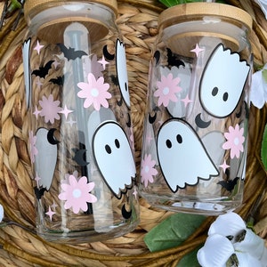 May include: Two clear glass tumblers with bamboo lids and black and white ghost, bat, and flower designs. Each tumbler has a black straw.