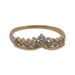 May include: A gold ring with a crown design featuring clear gemstones. The ring is a delicate piece of jewellery.