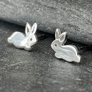 Op de afbeelding: Een paar zilveren oorbelletjes in de vorm van een konijn. De oorbelletjes zijn klein en delicaat en hebben een eenvoudig, realistisch ontwerp.