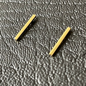 Könnte beinhalten: Ein Paar goldene Barren-Ohrringe. Die Ohrringe sind schlicht und minimalistisch im Design.