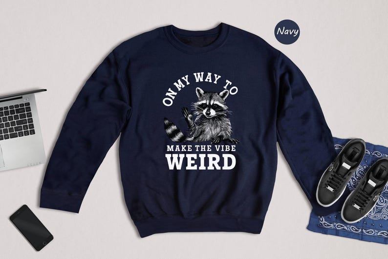 a sweater with a raccoon on it next to a laptop