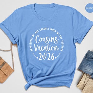A blue t-shirt with a white text design that reads "Approximately we are trouble when we are together" and "Cousins vacation 2026" is displayed on a white background.