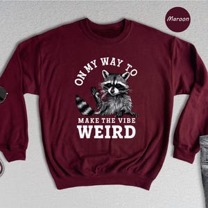 a maroon sweatshirt with a raccoon on it