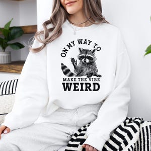 a woman wearing a white sweatshirt with a raccoon on it