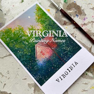 May include: A rectangular print featuring a painting of a small red house surrounded by green foliage, with the text "VIRGINIA Painting Names" and "VIRGINIA". A paintbrush rests on the surface next to the print.