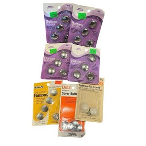 Puede incluir: Seis paquetes de botones para forrar de varias marcas, incluyendo Talon American, Dritz y Risdon. Los paquetes contienen componentes de botones de metal plateado y un paquete incluye cubiertas de plástico color crema, todos de tamaño 22 mm.