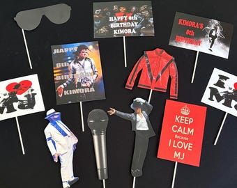 Puede incluir: Una colección de accesorios para fotomatón con temática de Michael Jackson en palitos, que incluye una chaqueta roja, un micrófono, gafas de sol y carteles rectangulares con texto como Happy 8th Birthday Kimora y Keep Calm Because I Love MJ.