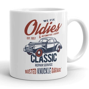 Puede incluir: Taza de cerámica blanca con un diseño rojo, blanco y azul. La taza presenta una ilustración de un automóvil antiguo y el texto "We Fix Oldies & Automotive Legends Est. 1957 Classic Repair Service Busted Knuckle Garage".