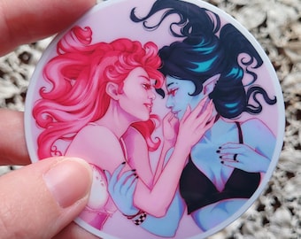 May include: A round sticker featuring two figures in a romantic embrace. One figure has red hair and the other has dark blue hair. The figures are set against a pink background.