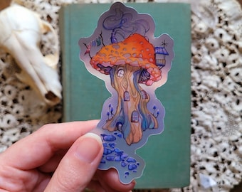 May include: A whimsical mushroom house sticker with a red and orange cap, a brown trunk with windows, and blue and purple details. The sticker is on a green background.
