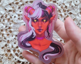 May include: A sticker featuring a digital illustration of a red-skinned person with white and black hair, yellow eyes, and pink horns. The person is wearing a pink choker and has a nose ring. The sticker has a holographic finish and includes the text "@flossy_arts".
