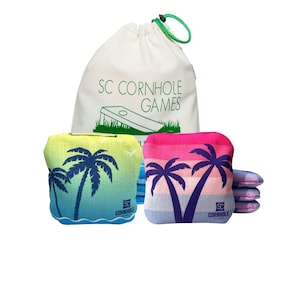 May include: A set of cornhole game bags with a drawstring bag. The bags feature a gradient design with palm tree silhouettes. The drawstring bag is white with the text "SC CORNHOLE GAMES" and a cornhole board graphic.