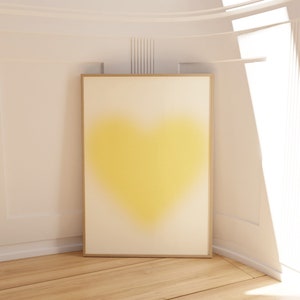May include: A framed abstract painting of a yellow heart shape on a white background.