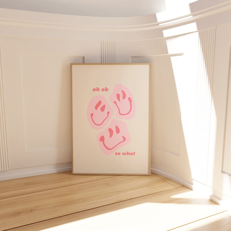 May include: A white poster with a gold frame features three pink smiley faces with the text "oh ok" and "so what" in pink.