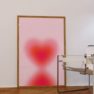 May include: A framed print with a pink background and a blurred red heart shape in the center.