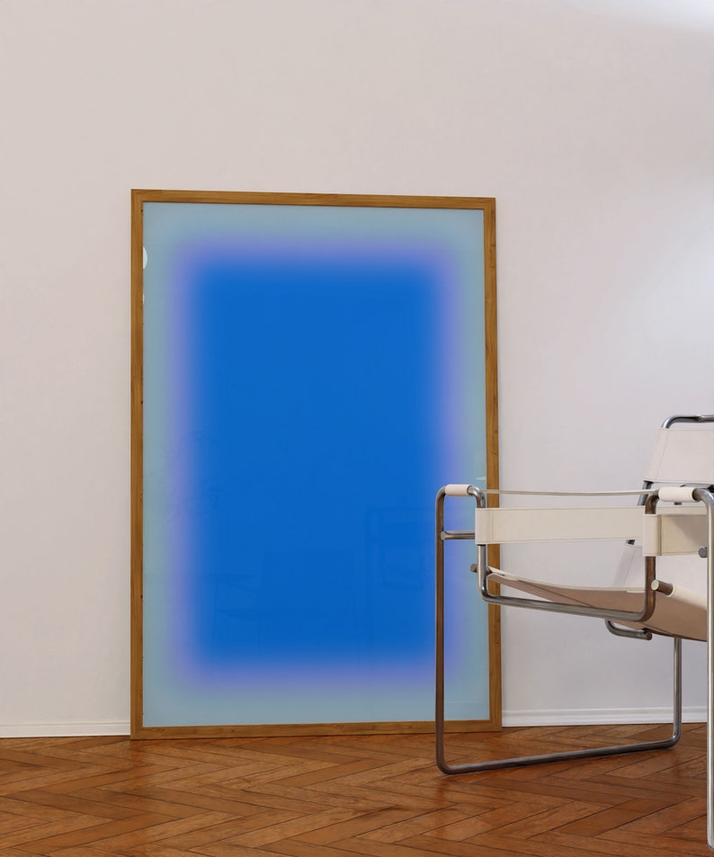 May include: A framed abstract art print with a blue gradient background and a wooden frame. The print is hanging on a white wall next to a white chair.