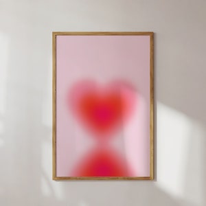 May include: A framed print with a pink background and a blurry red heart shape in the center.