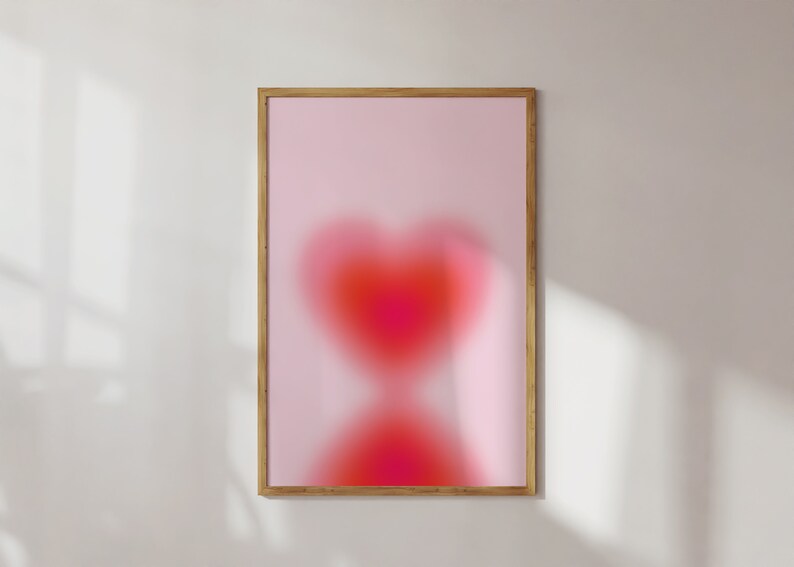 May include: A framed print with a pink background and a blurry red heart shape in the center.