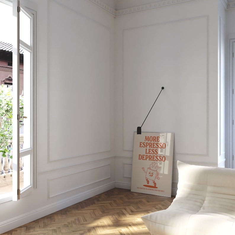 May include: A framed poster with the text "MORE ESPRESSO LESS DEPRESSO" hangs on a white wall. The poster features a cartoon coffee cup character. The room has a white chair, a window, and a wooden floor.