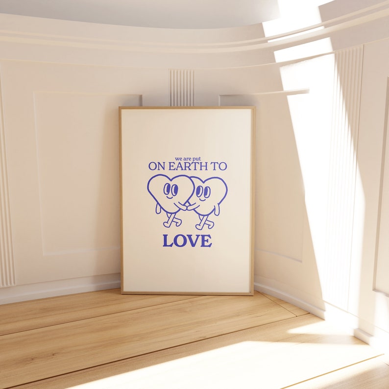 May include: A white poster with a blue graphic of two hearts holding hands. The text on the poster reads "we are put on earth to love".