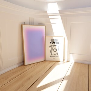K&ouml;nnte beinhalten: Zwei gerahmte Drucke an einer wei&szlig;en Wand mit einem Holzboden. Der Druck links ist ein Farbverlauf von Rosa, Lila und Blau. Der Druck rechts ist schwarzwei&szlig; und sagt "angel number" mit einer Zeichnung von vier Spielkarten mit der Nummer 7 auf jeder Karte und einem Herz in der Mitte. Der Text unter den Karten sagt "wonderful things are about to happen. luck."