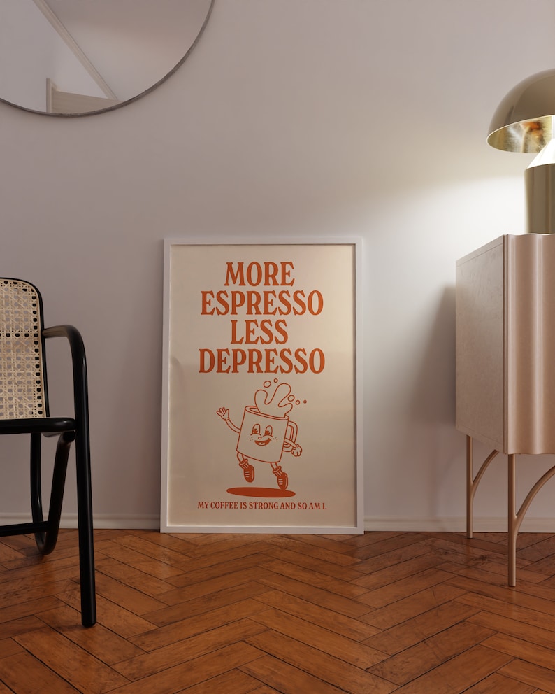 May include: A framed art print with the text "MORE ESPRESSO LESS DEPRESSO" in orange. The print features a cartoon coffee cup character with a smiling face and a splash of coffee. The text "MY COFFEE IS STRONG AND SO AM I" is at the bottom.