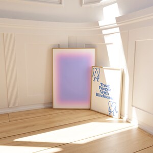 K&ouml;nnte beinhalten: Zwei gerahmte Drucke an einer wei&szlig;en Wand mit Holzboden. Der Druck links ist ein Farbverlauf von Rosa und Lila. Der Druck rechts ist wei&szlig; mit blauem Text, der "Treat People With Kindness." lautet, und einem blauen Comic-Herz mit Beinen.