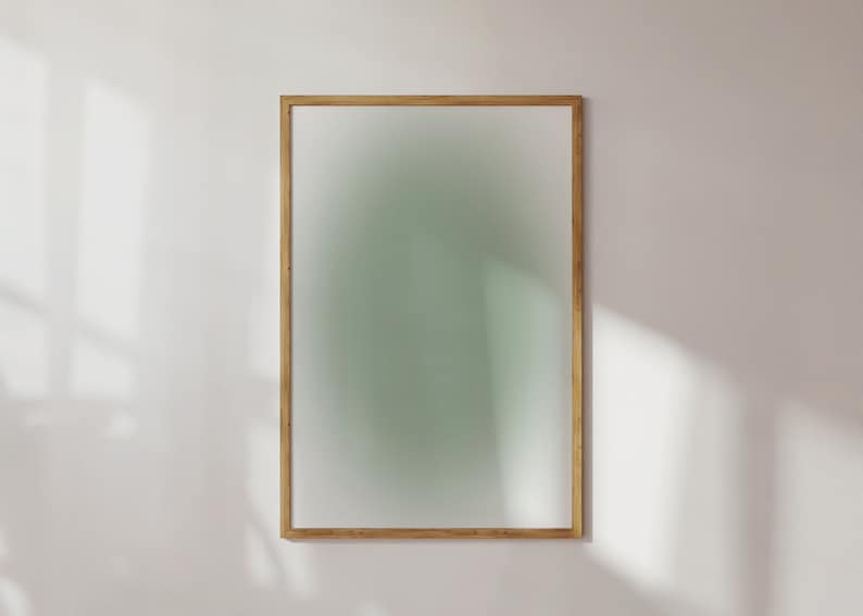 May include: A wooden frame with a light green, blurred background. The frame is hanging on a white wall.