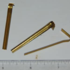May include: Three gold-coloured metal strips, each with a slight bend at one end. The strips are approximately 10 cm long.