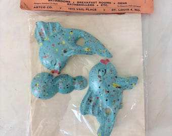 May include: Vintage "Fin Twins" decorative wall hangings. The blue figures are speckled with yellow, red, and black paint. The package includes the text "Fin Twins" and "The Decorative Darlings for Bathrooms, Breakfast Rooms, Rathskellers, etc."