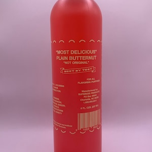 Könnte beinhalten: Eine rote Plastikflasche mit "Most Delicious" Plain Butternut-Aroma. Die Flasche ist mit "Best By Test" gekennzeichnet und hat einen Barcode. Sie enthält 8 Flüssigunzen (237 ml).