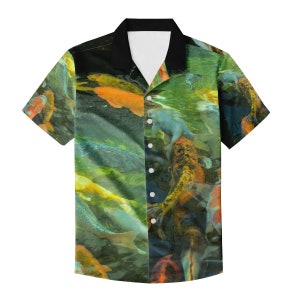Op de afbeelding: Korte mouwen button-down shirt met een levendige print van koi-vissen die in een vijver zwemmen. Het shirt heeft een zwarte kraag en een witte binnenkant. De koi-vissen zijn in tinten oranje, geel en wit.