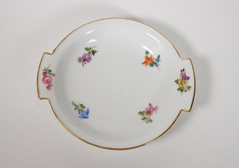 May include: A white porcelain serving dish with a gold rim and floral accents. The dish has two handles and is decorated with hand-painted flowers in shades of pink, purple, blue, yellow, and orange.