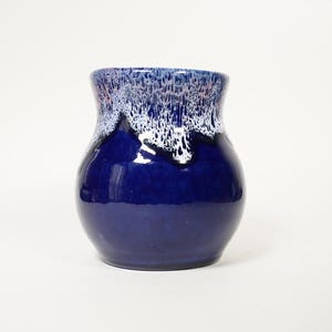 Peut inclure: Un vase en céramique bleu avec un glaçage blanc et rose. Le glaçage a un effet de goutte à goutte, créant un look unique et artistique.