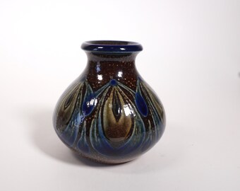 May include: A small, brown ceramic vase with a blue and green peacock feather design.