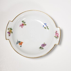 May include: A white porcelain serving dish with two handles and a gold rim. The dish is decorated with hand-painted floral motifs in shades of pink, blue, yellow, and orange.