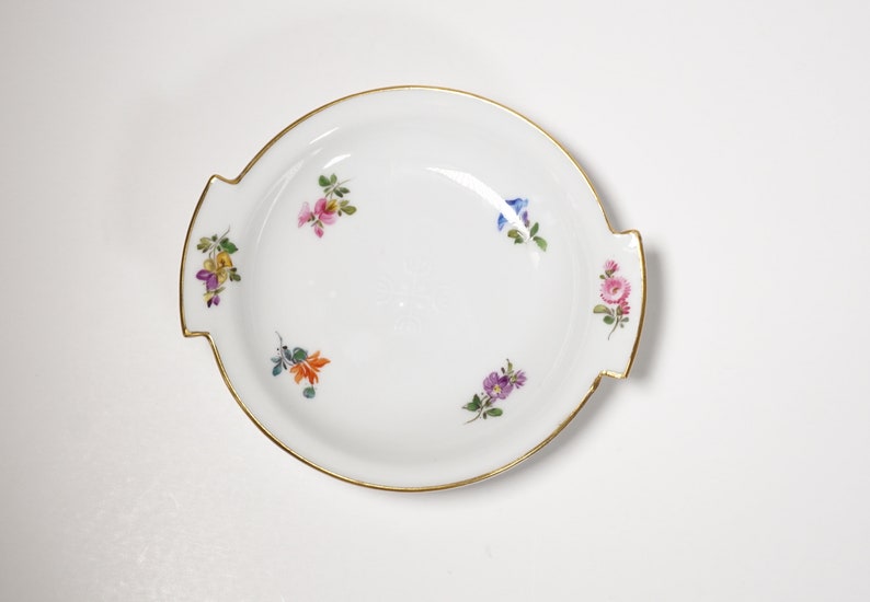 May include: A white porcelain serving dish with two handles and a gold rim. The dish is decorated with hand-painted floral motifs in shades of pink, blue, yellow, and orange.