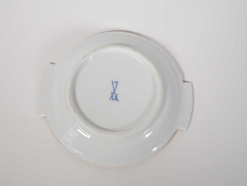 May include: White porcelain saucer with a blue and white mark on the bottom. The mark is a crossed sword with the letter 'V' above it.