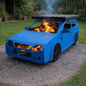 Puede incluir: Una barbacoa azul con forma de coche con llamas en su interior. La barbacoa tiene una parte superior negra y ruedas negras. El humo se eleva de la barbacoa, lo que indica que está en uso. La barbacoa está en un patio de piedra en un jardín.