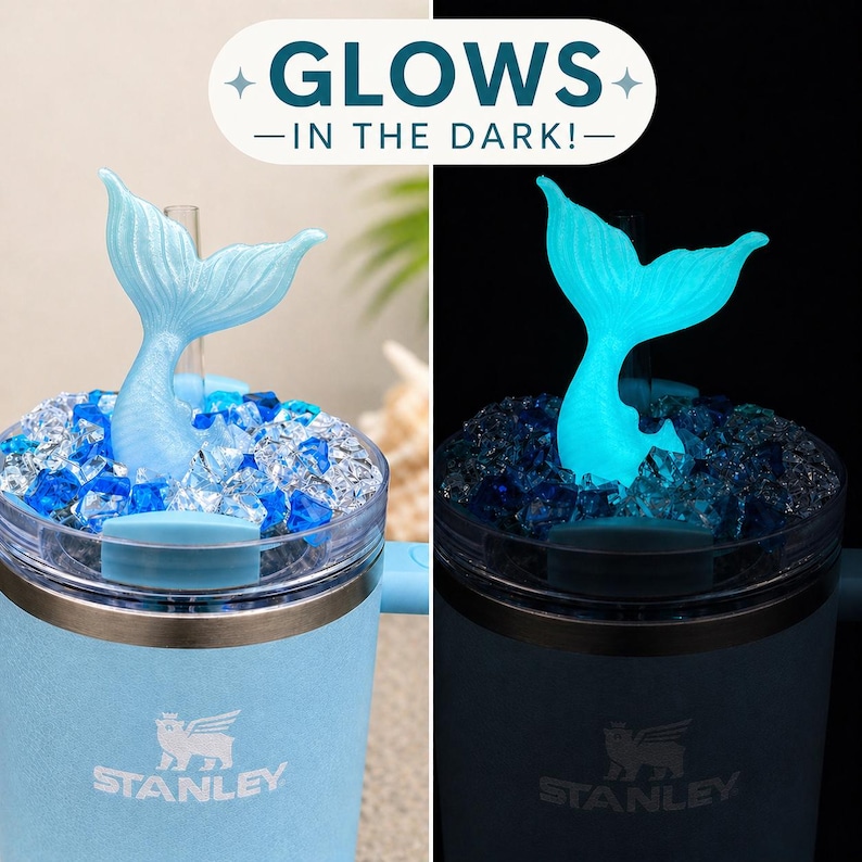 Op de afbeelding: Lichtblauwe Stanley-beker met een zeemeerminstaart-opzetstuk. De zeemeerminstaart en de blauwe stenen eromheen gloeien in het donker. De tekst "GLOWS - IN THE DARK!" staat bovenaan.
