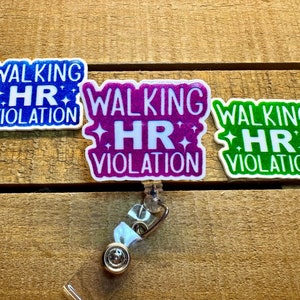 Peut inclure: Trois porte-badges colorés avec le texte "Walking HR Violation" en lettres blanches. Les porte-badges sont sur une surface en bois.
