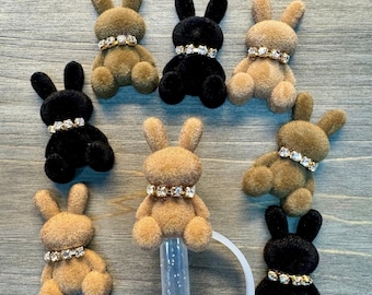 May include: A set of ten plush bunny rabbit charms with rhinestones. The charms are in three colors: brown, black, and beige. The charms are all the same size and shape, and they have a small loop at the top for attaching to a keychain or other item.
