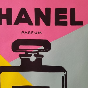 May include: A black and white illustration of a Chanel perfume bottle with the words "CHANEL" and "N&deg;5" on the label. The background is a pink, grey, and yellow colour scheme.