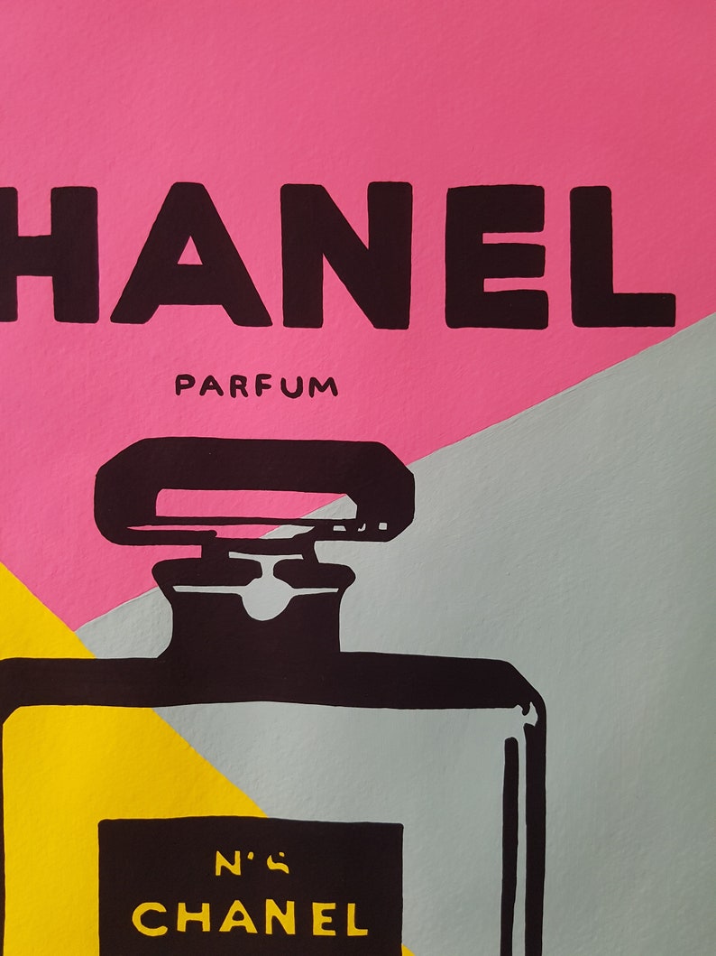 May include: A black and white illustration of a Chanel perfume bottle with the words "CHANEL" and "N&deg;5" on the label. The background is a pink, grey, and yellow colour scheme.