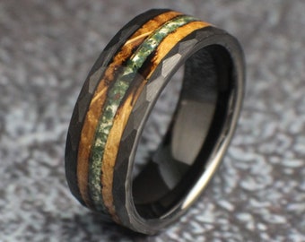 May include: A black tungsten carbide ring with a hammered finish and a wood inlay. The inlay features a green and brown pattern.