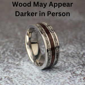 Puede incluir: Un anillo de plata con una incrustaci&oacute;n de madera marr&oacute;n oscura y una textura moteada plateada. El texto "Wood May Appear Darker in Person" es visible sobre el anillo.